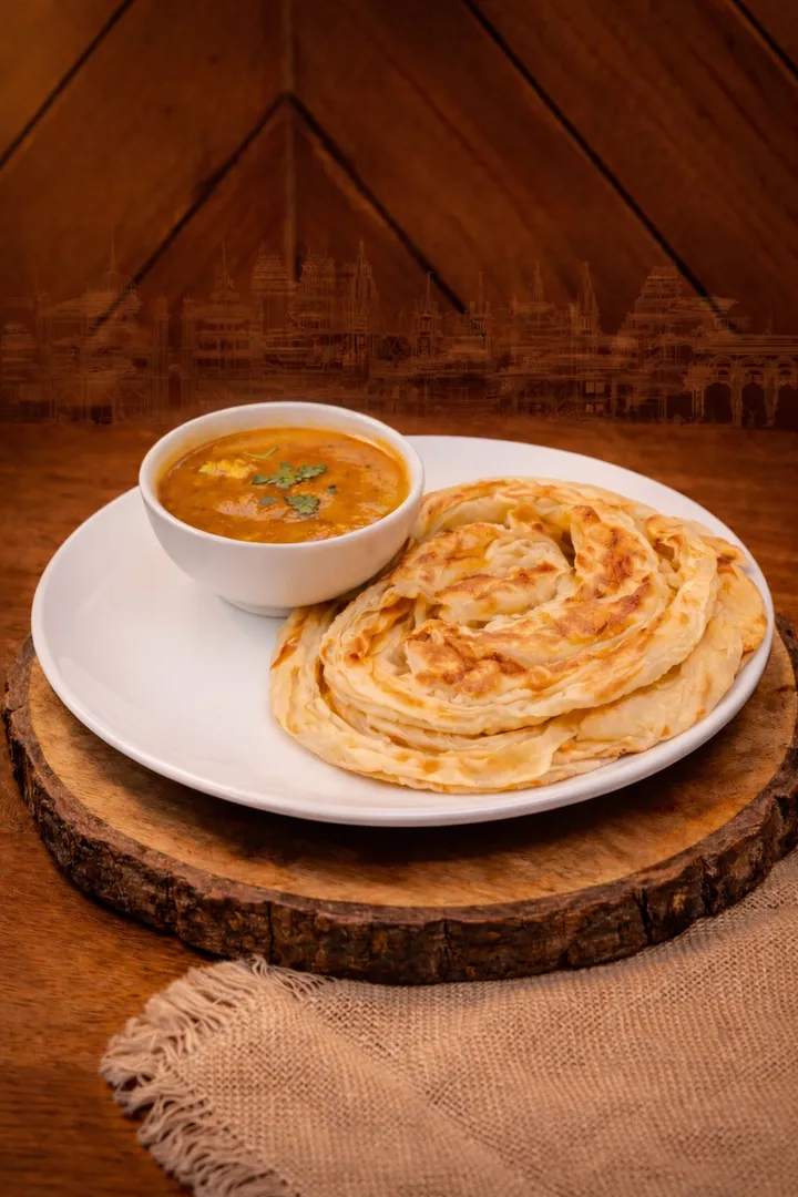 Bun Parotta served with salna curry at Parotta Palace — soft, pillowy, cloud-like South Indian flatbread on a rustic wooden board