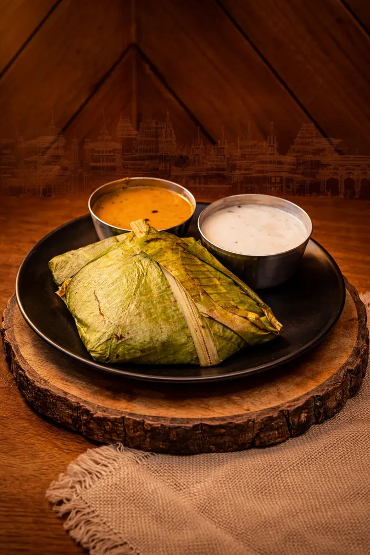 Kizhi Parotta wrapped in banana leaf with salna and coconut chutney at Parotta Palace — traditional steamed South Indian parotta bundle